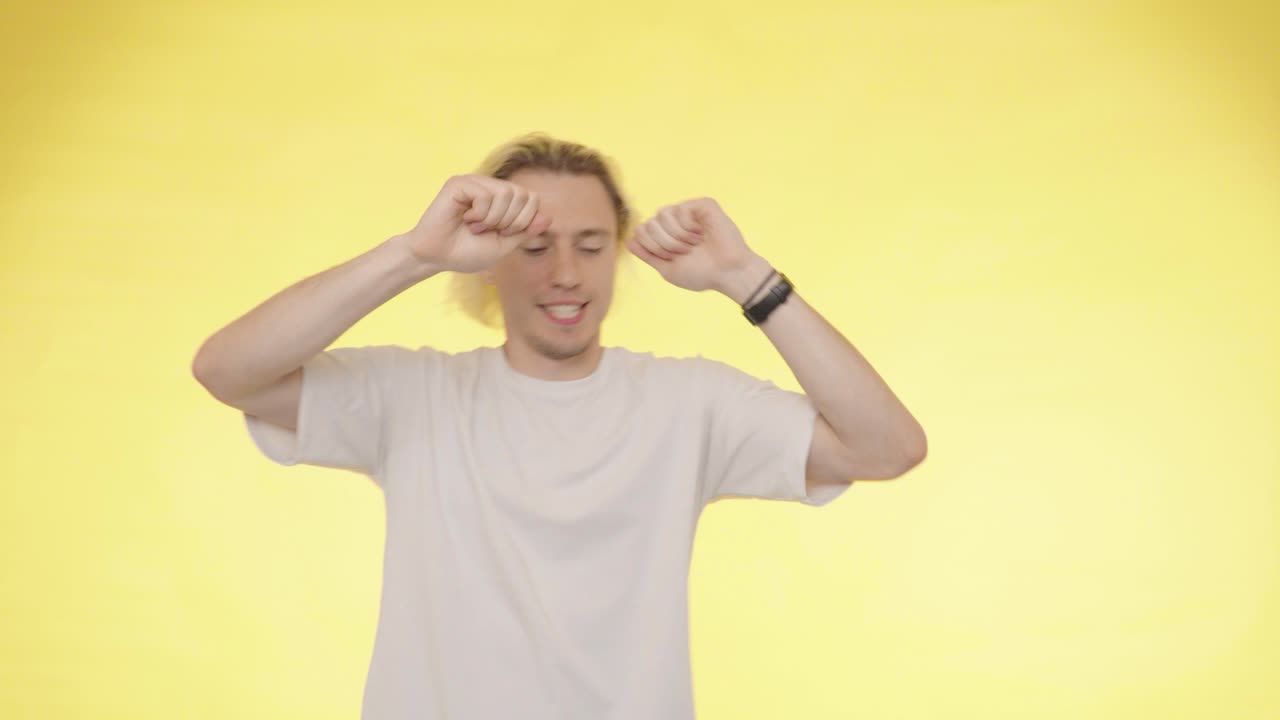 행복한 자신감있는 금발 긴 머리 남자가 그의 성공을 축하하고 춤추고 있습니다.