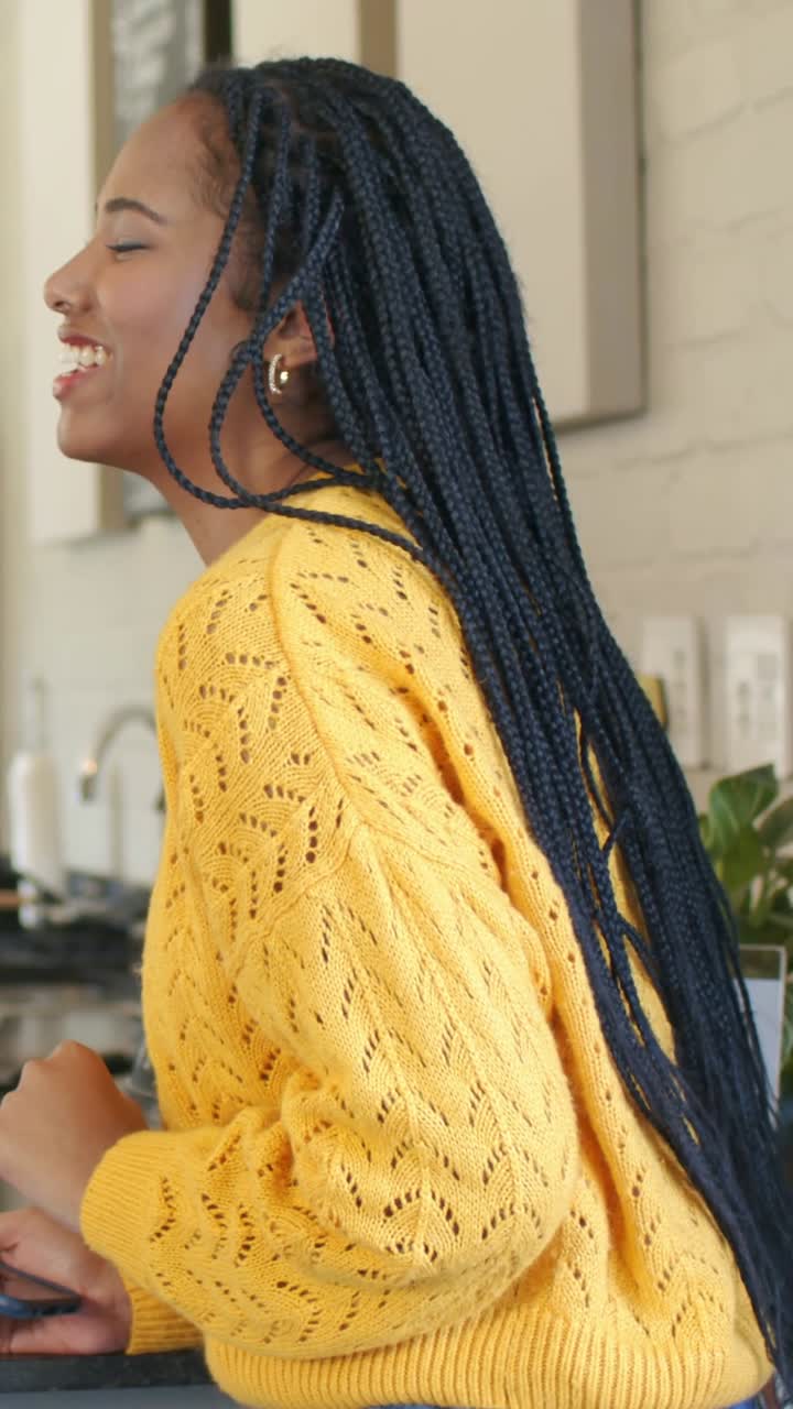 Video verticale: Membro dello staff che chiama una donna con top giallo e jeans che ride al bancone del caffè con un terminale.