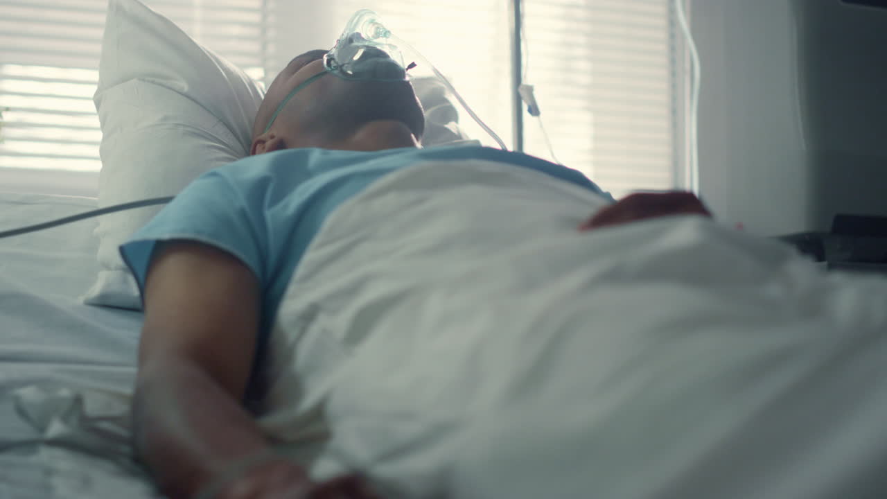 Ill man breathing oxygen mask in clinic ward. Pulse oximeter on finger closeup.