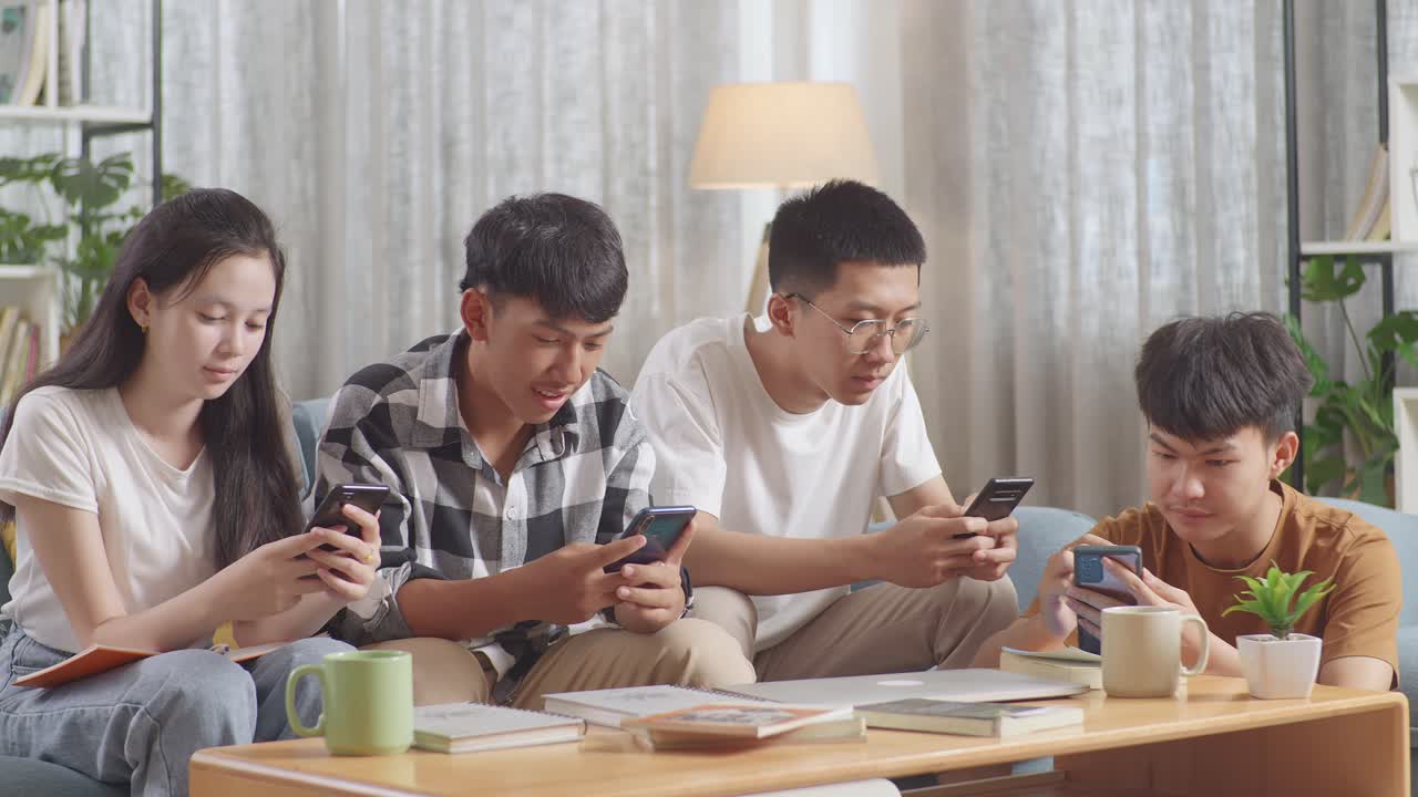 책과 노트북을 가지고 스마트폰을 사용하는 아시아 십대 그룹, 집에서 공부한 후 휴식 시간