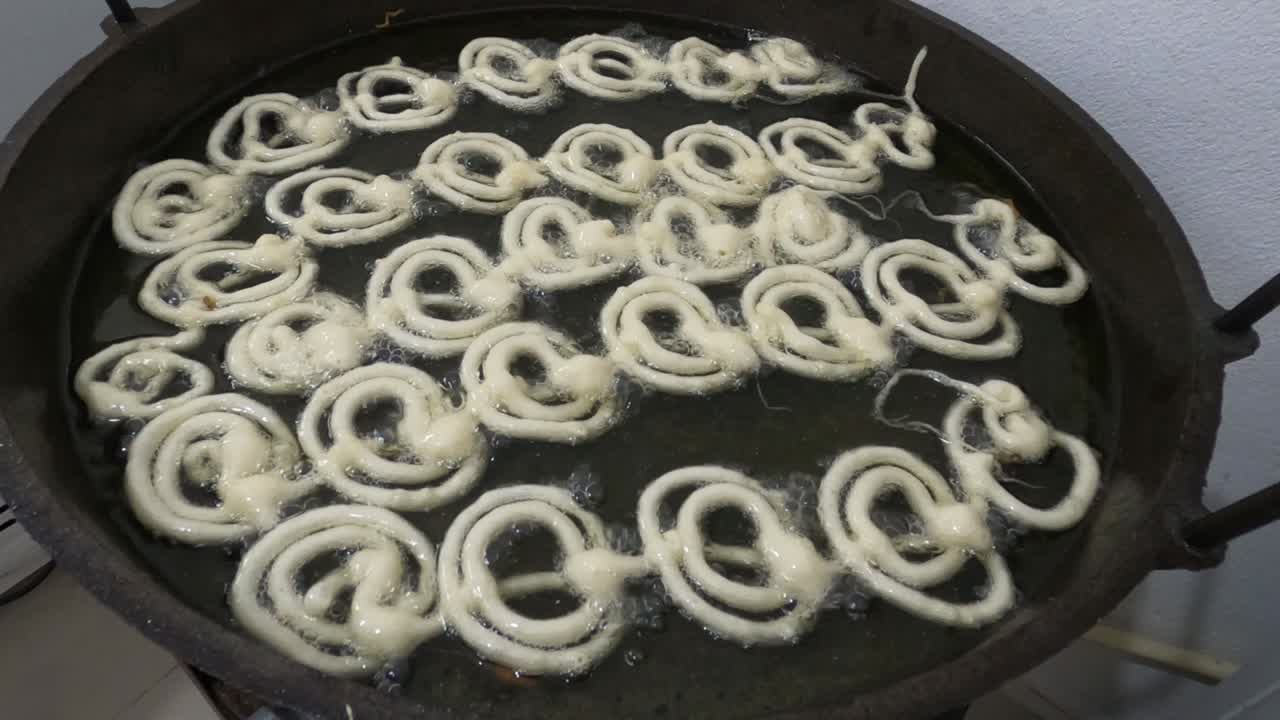Raw jilapi deep frying 4k video clip.Jilapi making on a hot big pan.Jalebi, also known as jilapi, jilebi, jilipi, zulbia, jerry, mushabak, or zalabia, is a popular Indian sweet snack.