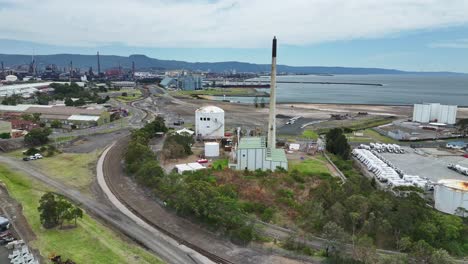 aerial of port kembla industrial area with large chimney storage tanks and wharves beyond