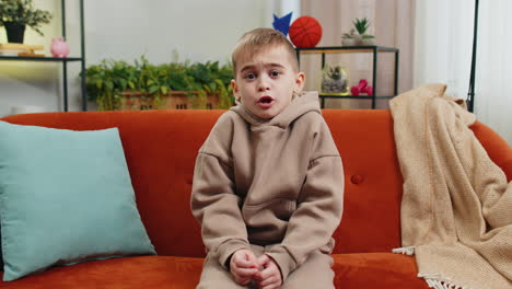 a young boy sitting on a couch looking at the camera