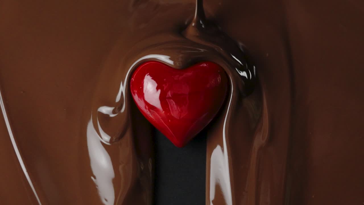 gotas de chocolate con leche en el corazón rojo en cámara lenta