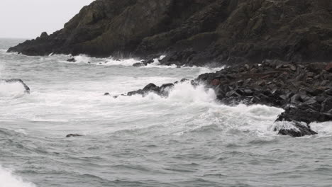 rough autumn tide crashes in on dark rocks in the small village of port patrick, dumfries and galloway, scotland