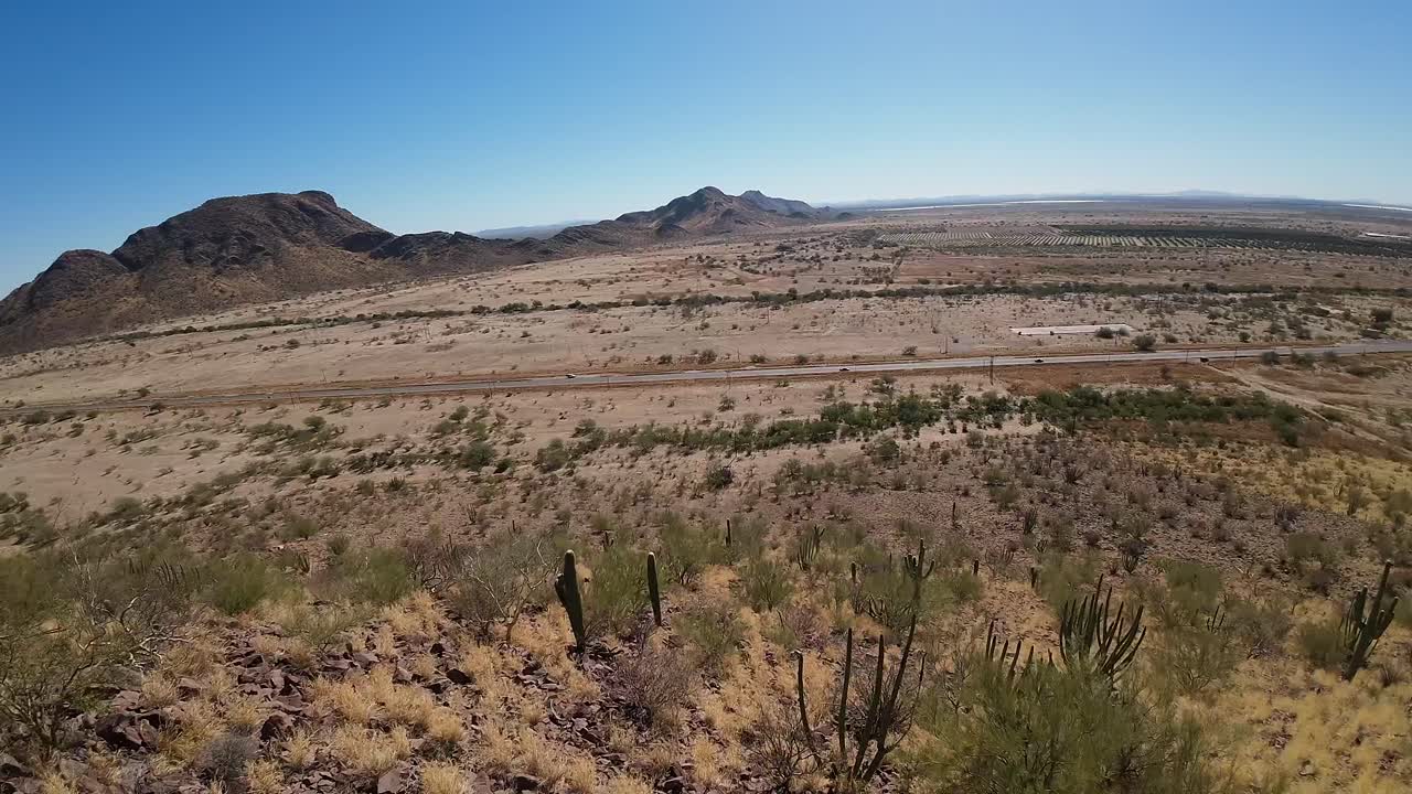 Drone flight down desert mountain with lots of sun