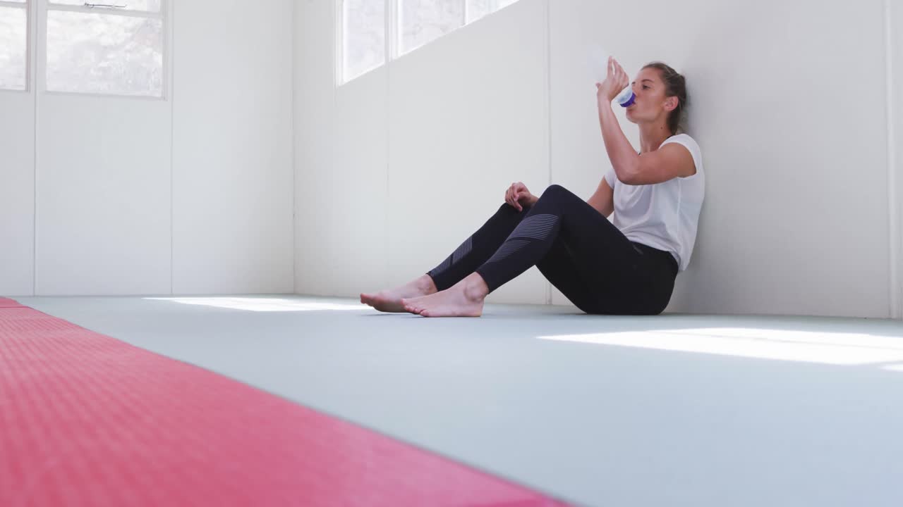 mujer caucásica bebiendo agua después del entrenamiento