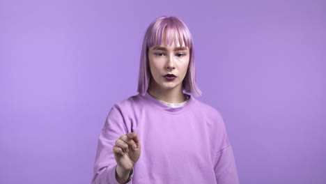 young unusual woman using touchscreen of smartphone or tablet. she swiping on violet studio background. technology, interface concept.