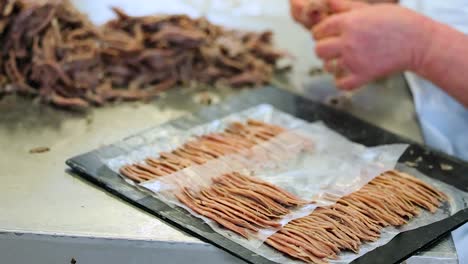 processed fish pieces are laid out on tray by worker in fish processing factory