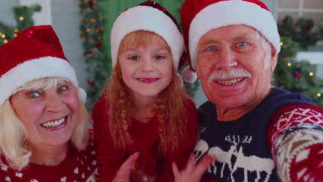 POV-shot-of-senior-grandparents-with-grandchild-girl-kid-taking-selfie-on-mobile-phone-on-Christmas