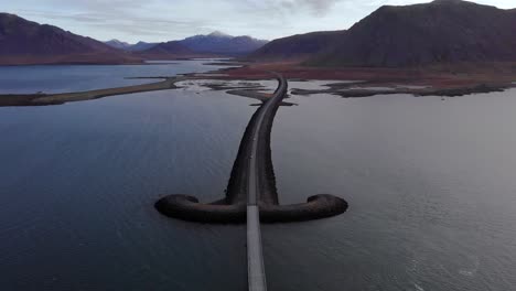 aerial 4k view over an icelandic road with a sword shape over the ocean, surrounded by mountain landscape, iceland, europe, tilt up establishing shot