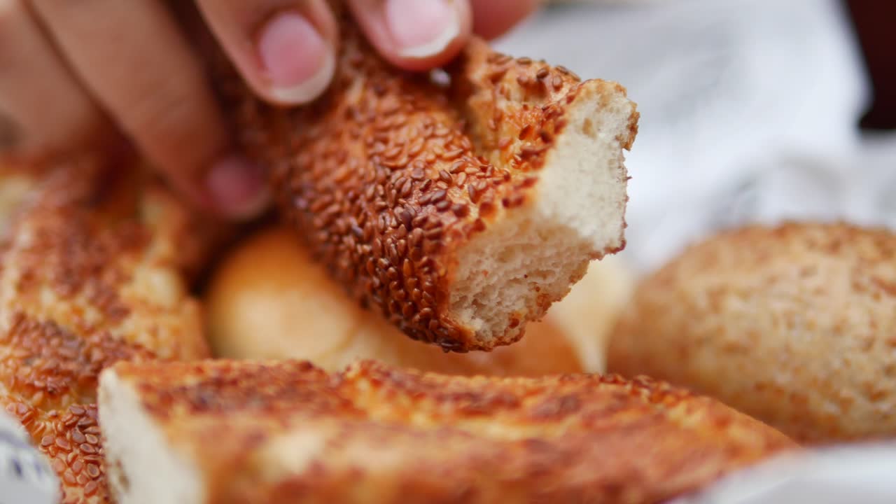 primer plano de una persona rompiendo un pan de semillas de sésamo