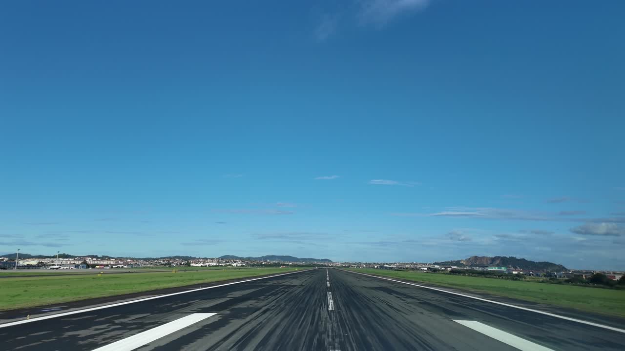 An immersive pilot’s eye view FPV in a real time landing at Santander airport runway, surroended by green fileds , under a bright, unclouded blue sky