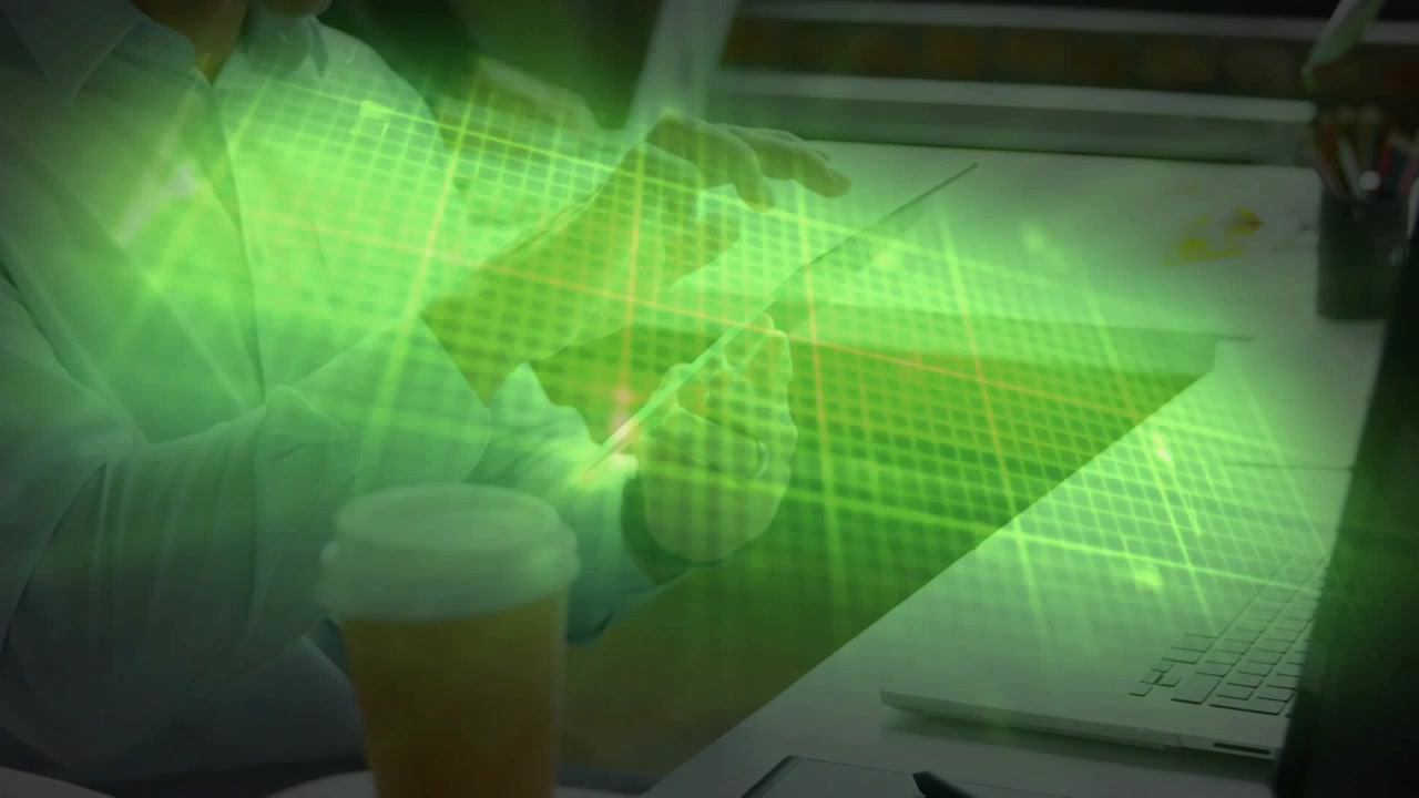 Man seated desk tapping phone near laptop activating green grid overlay while analyzing tech data