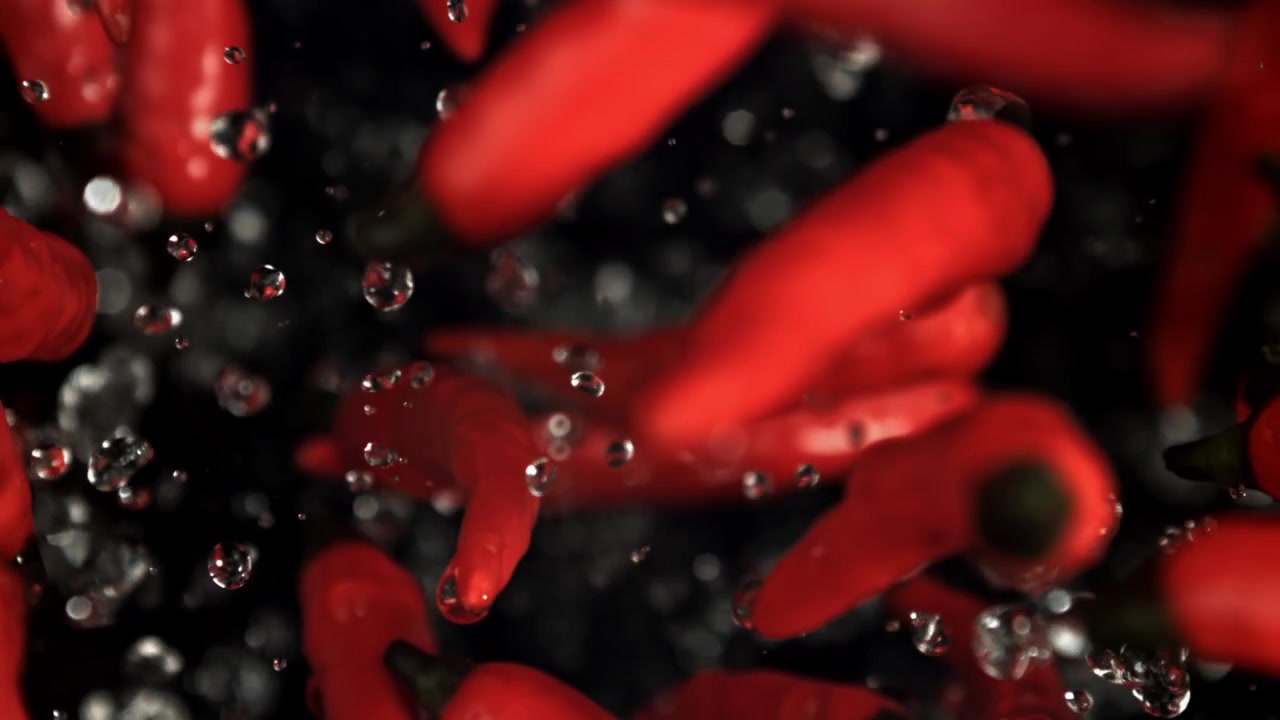 Red Chili Peppers with Water Drops Splashing in Slow Motion