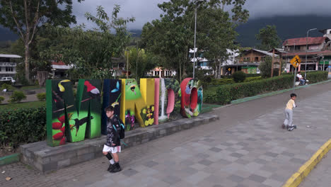 colorful art installation on sidewalk near park with children passing, mindo ecuador