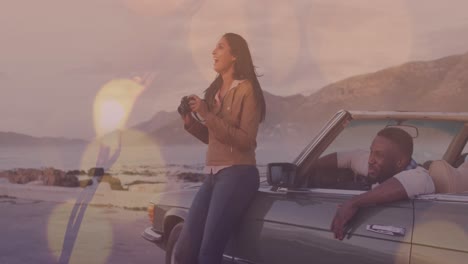 animation of light spots over happy diverse couple taking photo with car