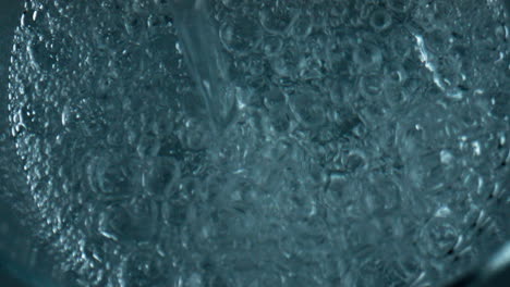 bubbling water pouring glass top view. closeup air bubbles rising exploding