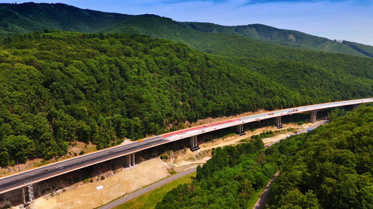 Building a forest overpass. Workers are building a new highway that stretches over a beautiful green landscape on a bright sunny day