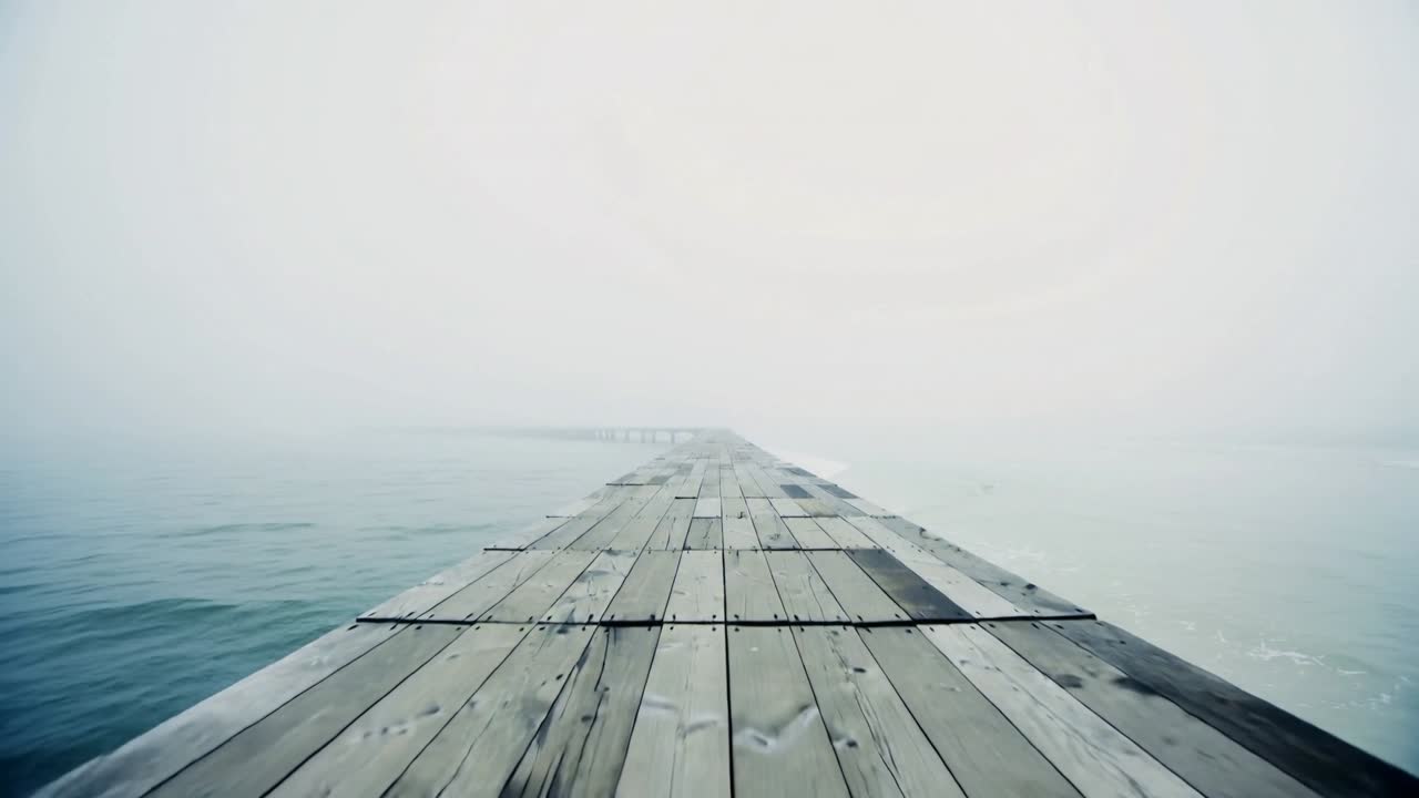 Camera dolly starting tracking along wooden pier showing planks nails ripples fog for designers