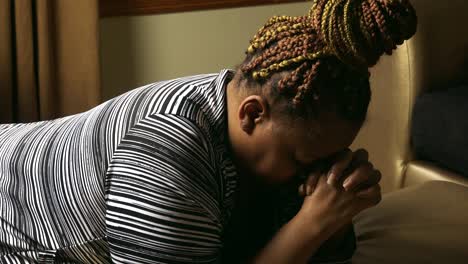 Black-woman-on-knees-in-living-room-praying-to-God-without-ceasing-Prayer-for-our-nation-and-world