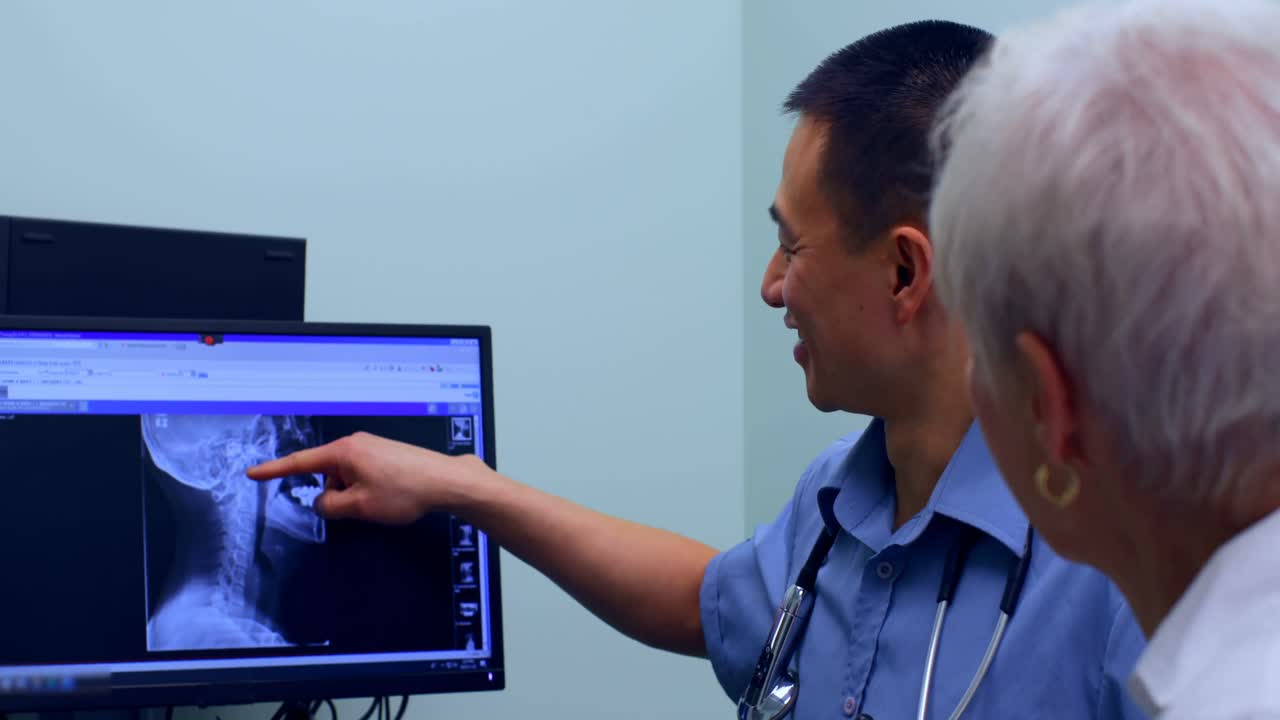Young Asian male doctor discussing over x-ray report on computer at clinic 4k