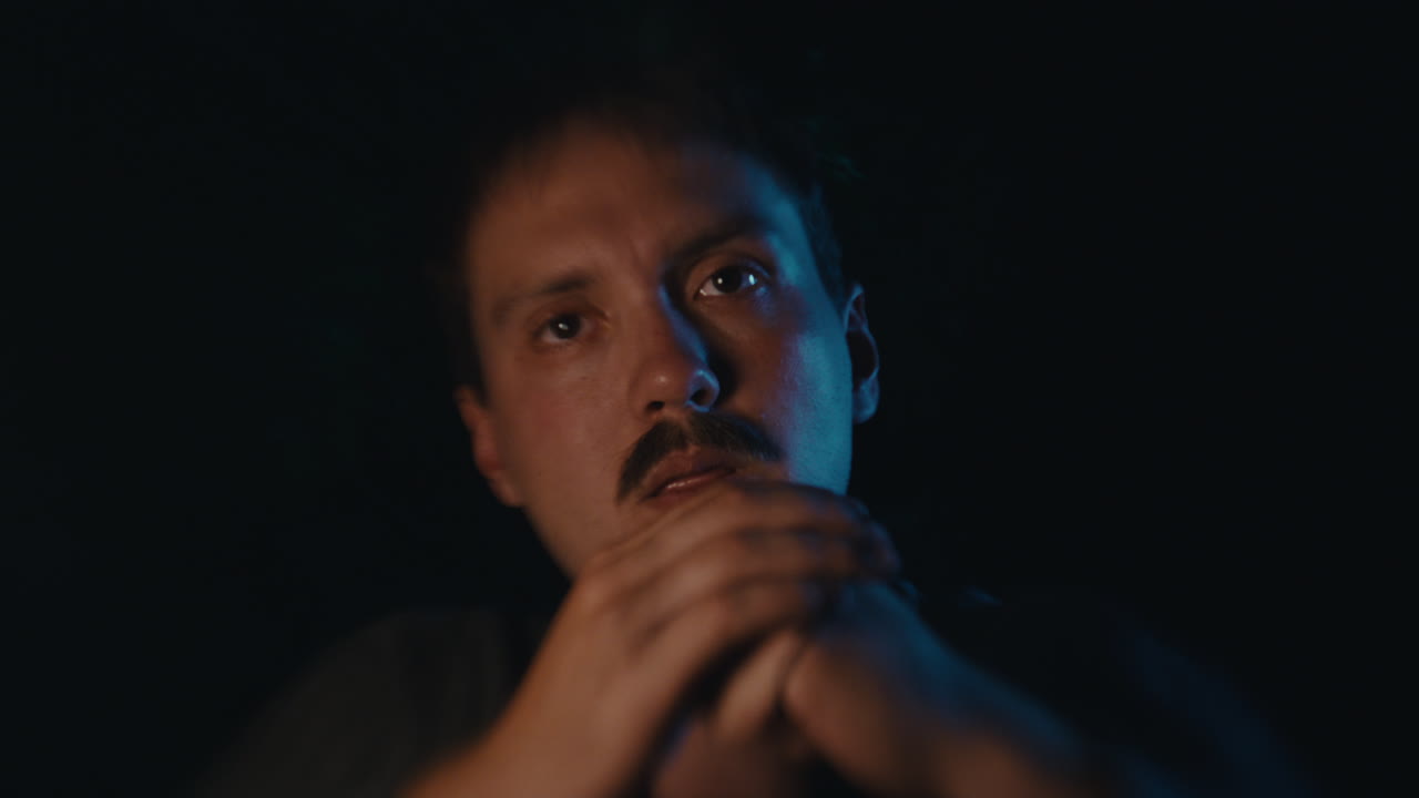 Man applying a fake mustache in low light