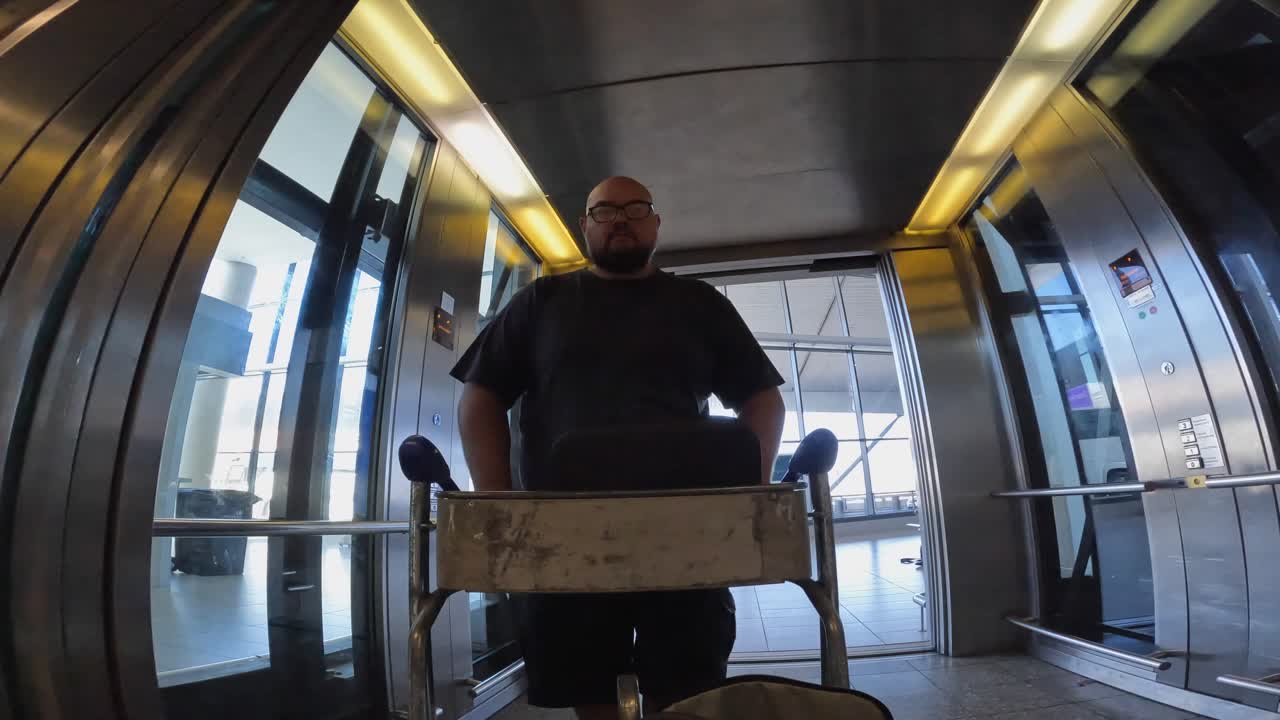 POV: man duwt bagagekar uit glazen lift op CPT-luchthaven