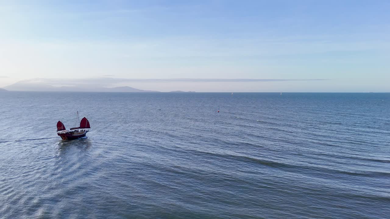 Aerial view of a boat departing a marina in Port Douglas, Australia, captured in serene morning light with calm ocean waters