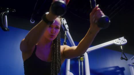 close up shot low angle, of a girl using a cable machine while giving an intense look on her face