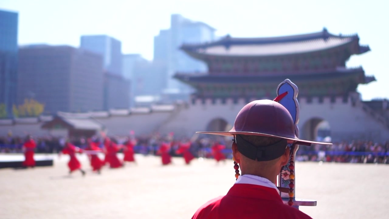 Gyeongbokgung'daki kraliyet muhafızının arkasından ağır çekim, arka planda savaş gösterisi.
