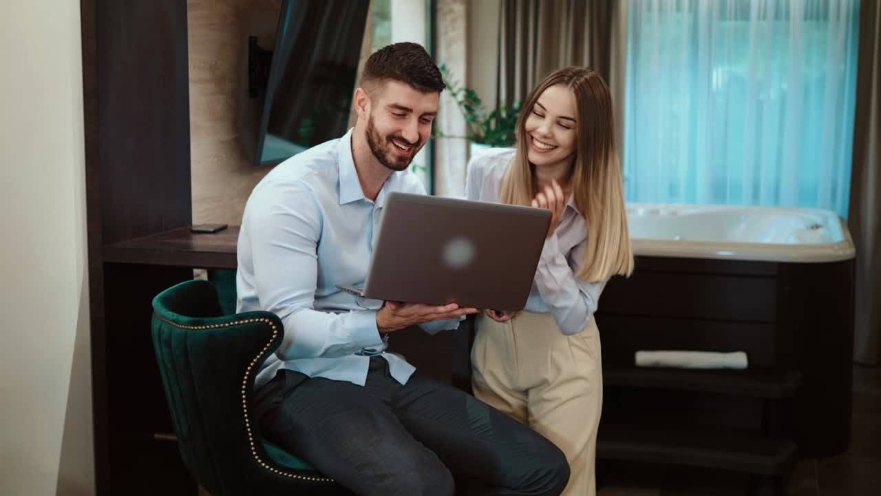 jóvenes colegas gerentes en un viaje de negocios trabajando en una computadora portátil en una habitación de hotel. sonriente joven pareja de negocios usando la computadora en el hotel