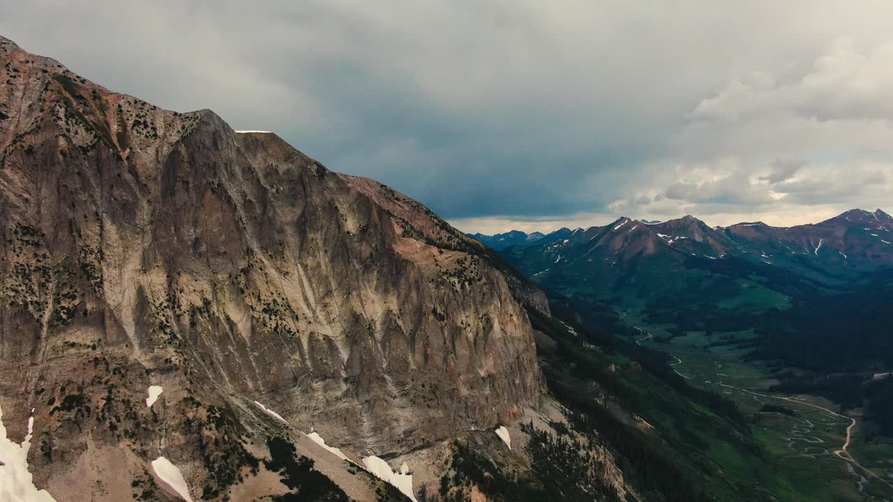imágenes de drones de una montaña rocosa junto a un valle alpino largo y profundo