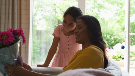 Daughter-Giving-Mother-Bunch-Of-Flowers-And-Homemade-Card-For-Birthday-Or-Mothers-Day-At-Home