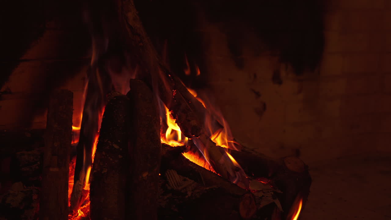 Wooden logs burning in fireplace. Cosy atmosphere of mantel at home at winter season. Firewood in flame indoors. Close-up.