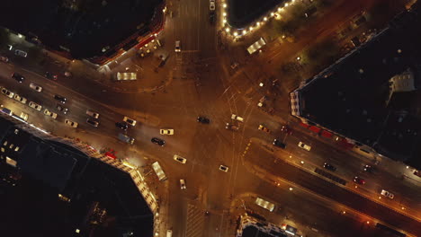 Top-View-of-Big-Intersection-at-Night-in-Berlin,-Germany-at-Rosenthaler-Platz-in-Mitte-District-in-Orange-City-light-with-Car-Traffic-Moving-in-Urban-Neighbourhood,-Aerial-Birds-Eye-Overhead-View