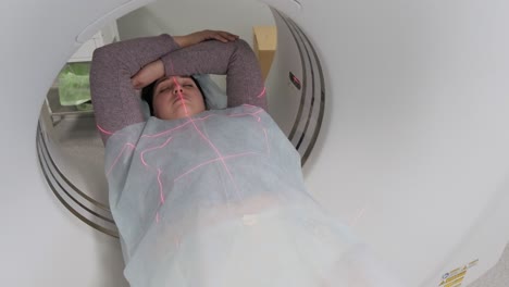 mujer acostada en el escáner de ct o mri durante la máquina de imágenes de su cuerpo, se enciende los rayos infrarrojos y la paciente pasa a través del círculo, grúa disparada de abajo hacia arriba, interior de la habitación, escena activa.