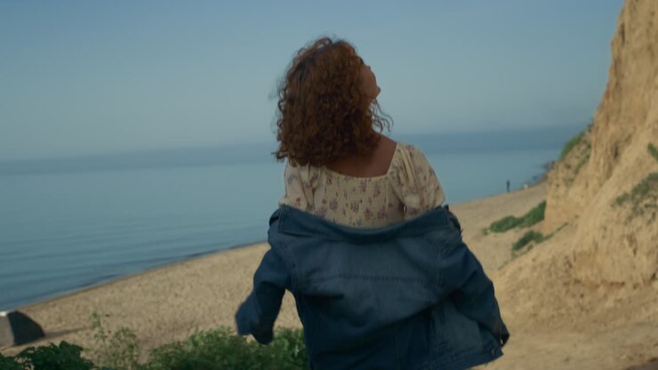 Carefree girl going down to beach. Happy smiling woman walking sea shore.