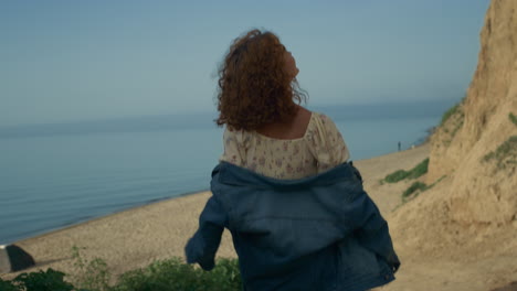 carefree girl going down to beach. happy smiling woman walking sea shore.