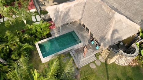 girl enjoying good weather in luxury villa hotel with private pool surrounded by palm trees