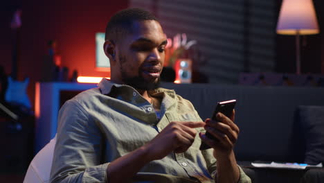 vertical video african american young guy enjoying break with his phone on sofa