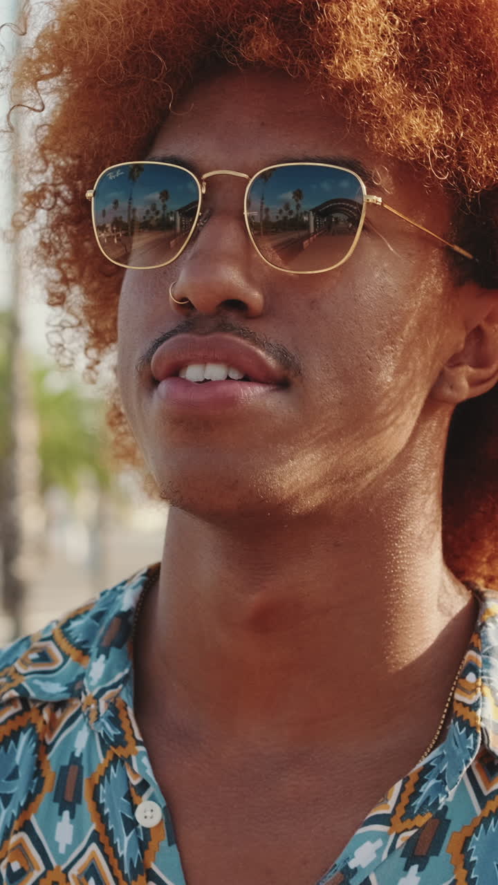 Giovane uomo alla moda con capelli ricci rossi che si mette un auricolare nell'orecchio.