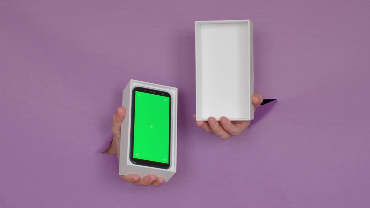 un nuevo teléfono con una pantalla verde en una caja en tus manos, sobre un fondo púrpura