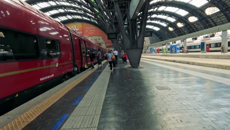 travelers boarding trains at milan's central station