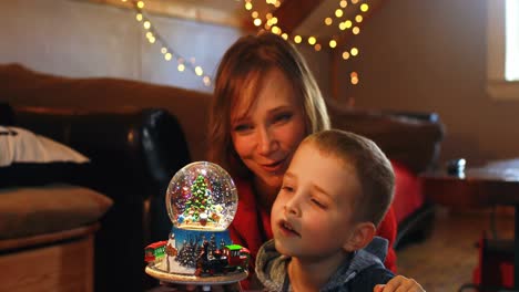madre e hijo jugando con juguete de bola de cristal durante la navidad 4k
