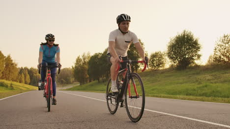 hard training.triathlete two cyclist training on road bicycle. two cyclist riding on road bike in city park and getting ready for triathlon.fit athlete intensive training two man and woman cycling before triathlon competition.