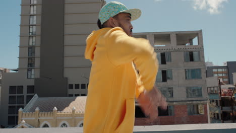 dancing-man-hip-hop-dancer-performing-freestyle-dance-moves-on-rooftop-in-city-wearing-yellow-hoodie