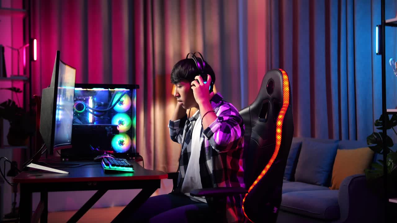 un adolescente asiático que usa auriculares y comienza a jugar videojuegos en la computadora