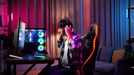 un adolescente asiático que usa auriculares y comienza a jugar videojuegos en la computadora