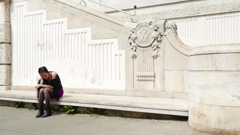 mujer asiática sentada al aire libre en arquitectura renacentista esperando tocar el cabello - cámara lenta